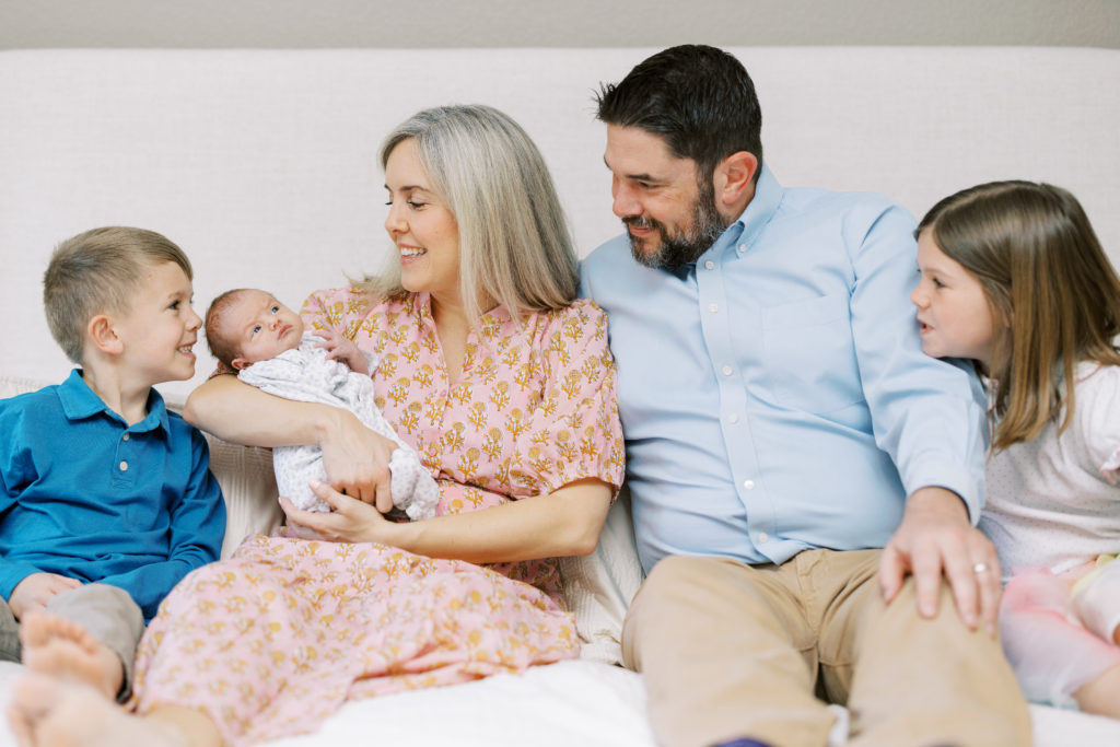 family of 5 posing for the newborn session on the bed