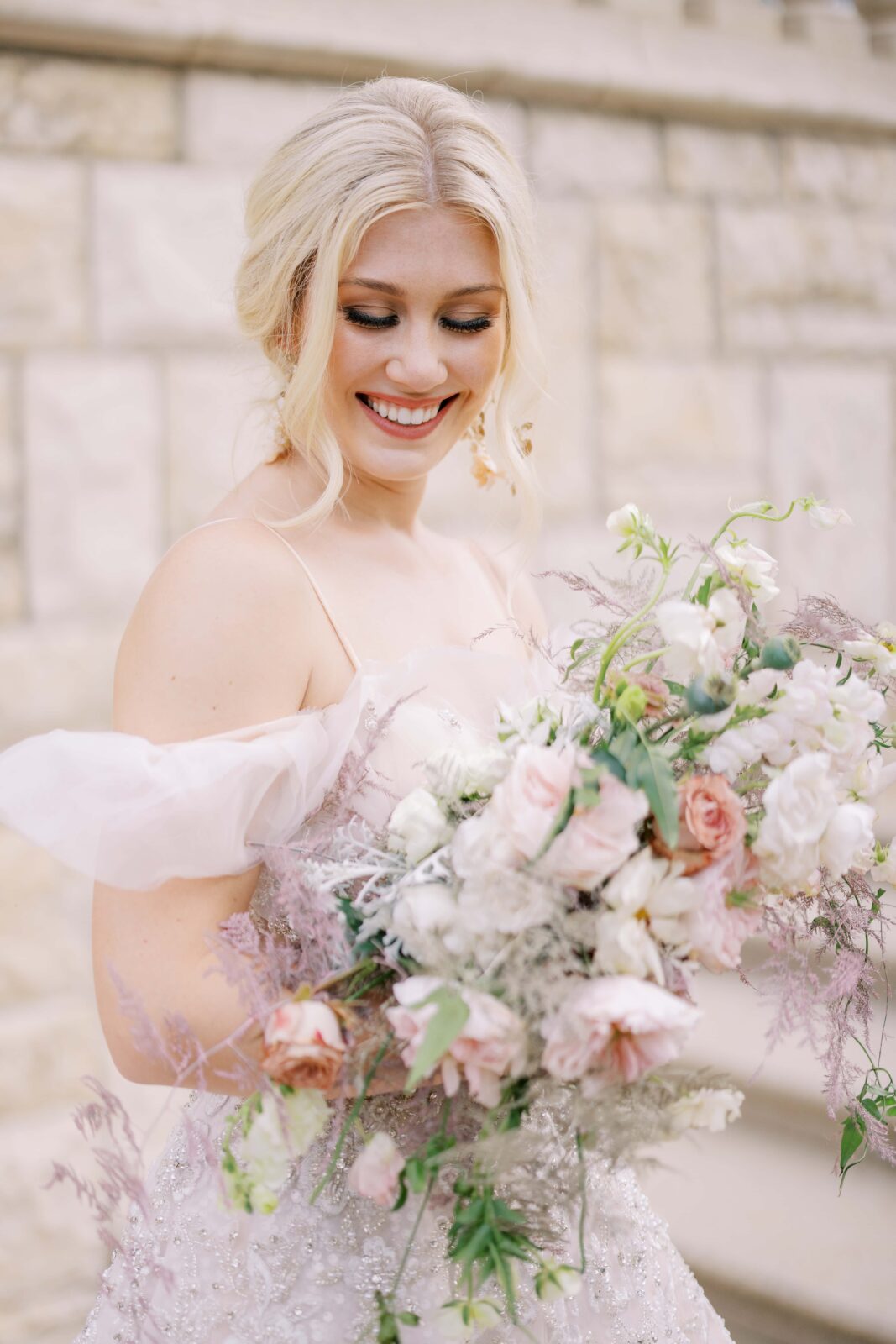 bride looking down at her bouquet and smiling while standing on the stairs of the olana backyard