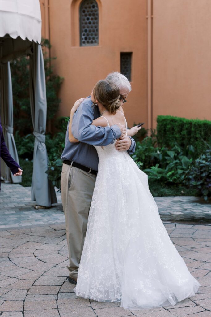 bride hugging her uncle in the courtyard of the rosewood mansion 