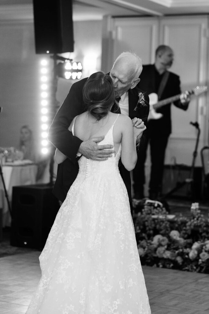 father of the bride kissing his daughter at her wedding during their first dance at the rosewood mansion
