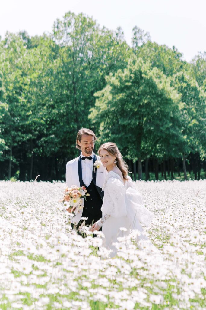 bride and groom in a daisy field at the chateau de champlâtreux during their france wedding