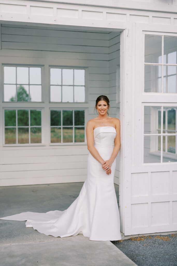 Bride smiling at the camera while leaning on the little house for her Davis and Grey Farms Bridal session 