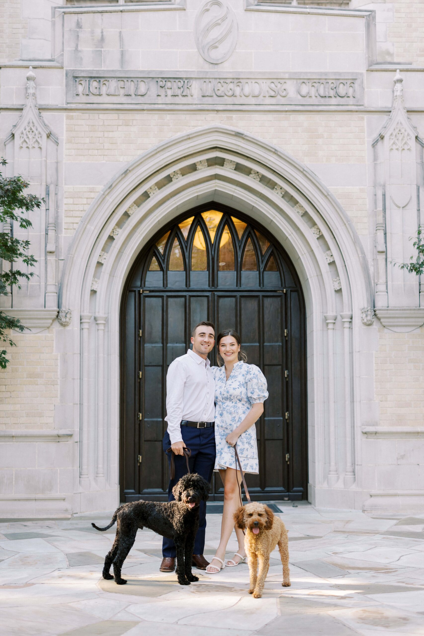 Couple standing with their two dogs for their engagement session at HPUMC in Dallas