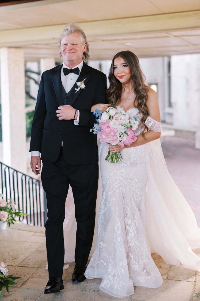 bride walking down the aisle with her father in law to be during her Intimate Wedding at Villa Antonia near Austin