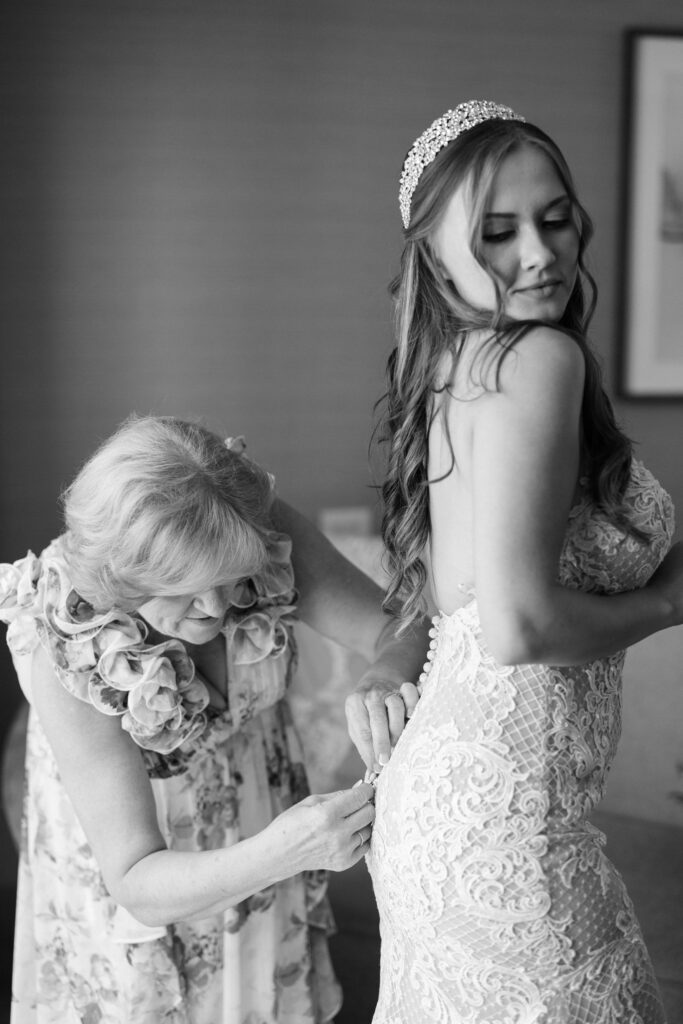 bride getting in her dress with the help of her mom at her Hotel Crescent Court wedding