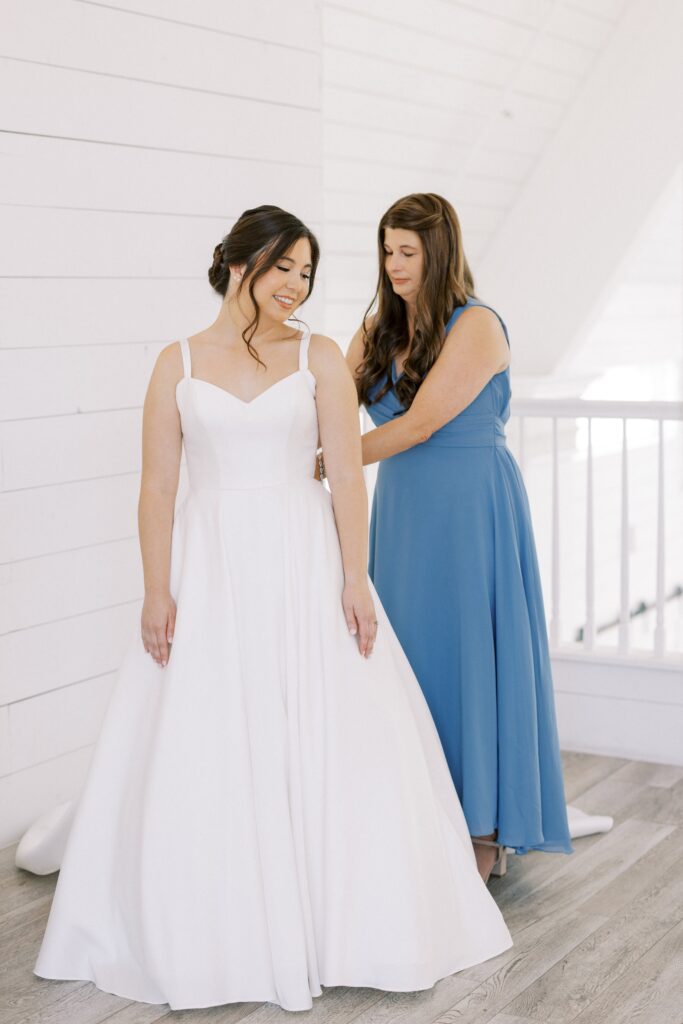 bride getting in her dress with her mom at The Nest at Ruth Farms