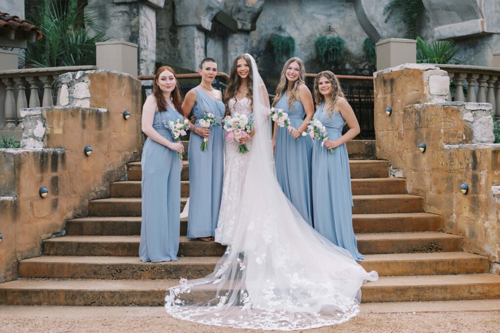 bride with her bridesmaids on the stairs in the courtyard at this Intimate Wedding at Villa Antonia near Austin