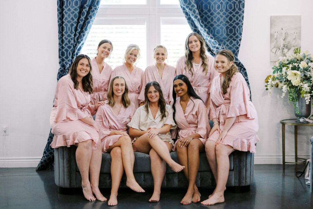 bridesmaids sitting on the couch in their pink matching pajamas at The Springs Event Venue Weatherford