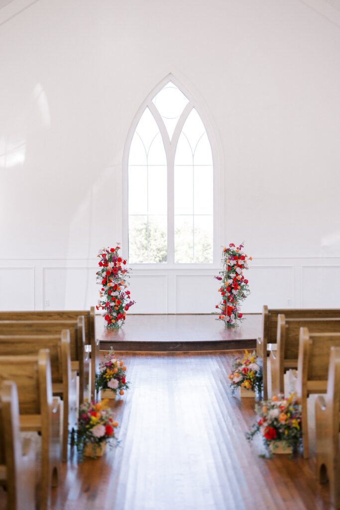 ceremony set up with vibrant red orange and yellow florals at the chapel of The Springs Event Venue Weatherford