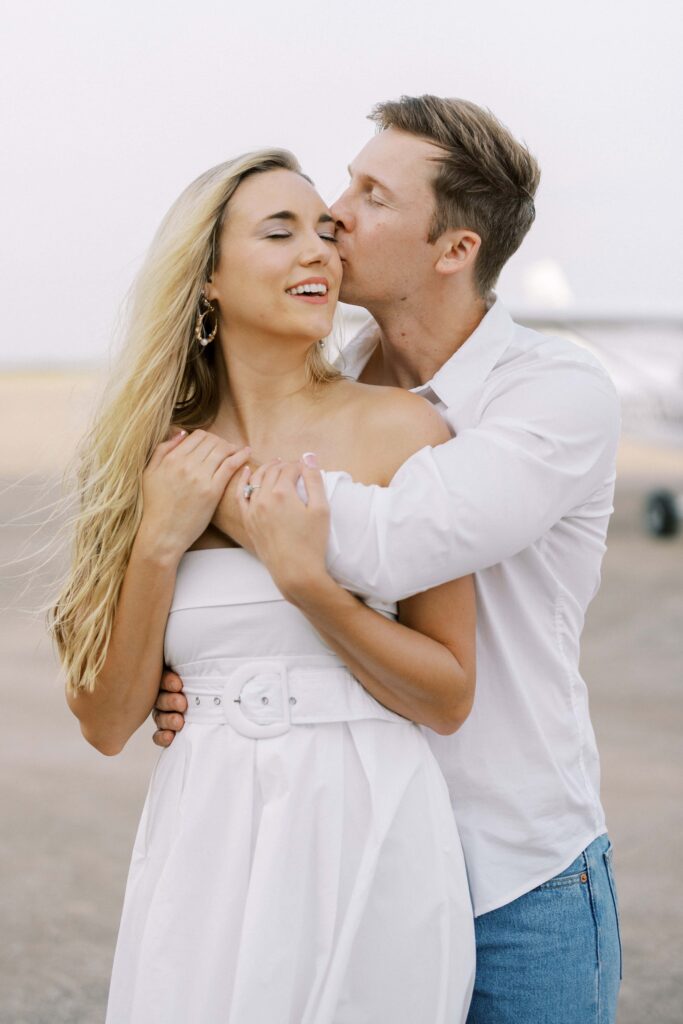 groom kissing the bride's cheek during their Airplane Engagement Session in Dallas-Fort Worth