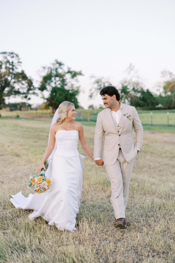 bride and groom walking hand in hand in the open fields during their Wedding at Chandelier Farms 