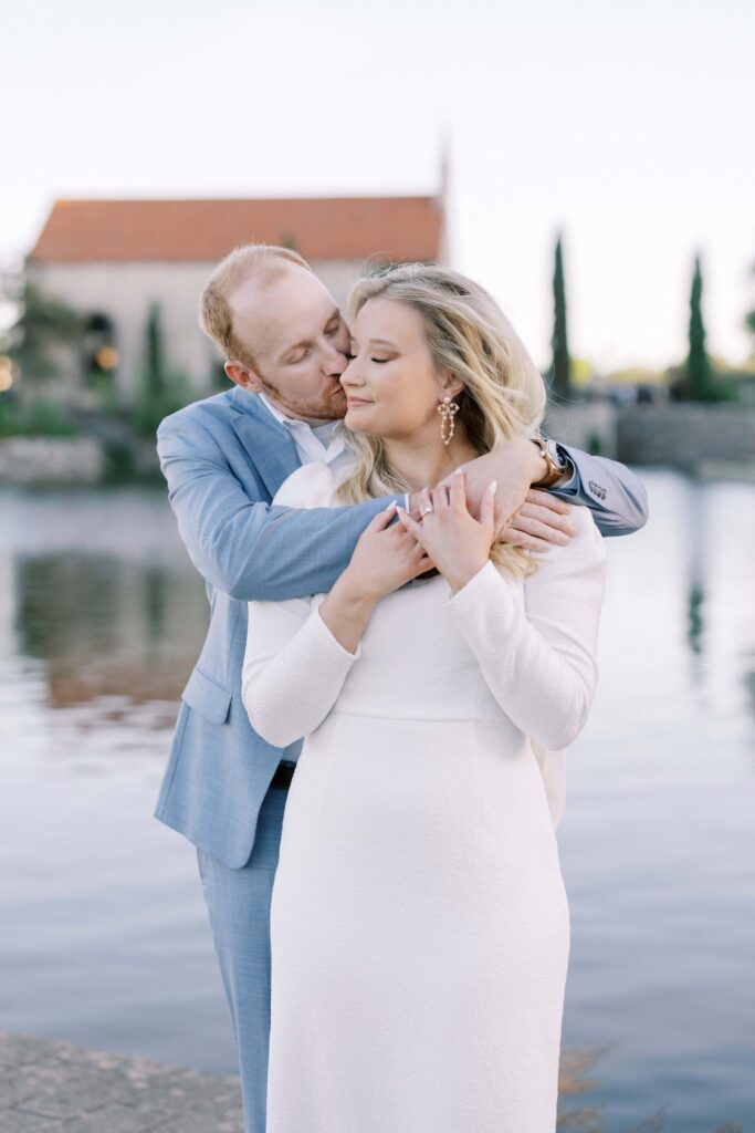 groom kissing the bride on the cheek at their Adriatica Village Engagement session