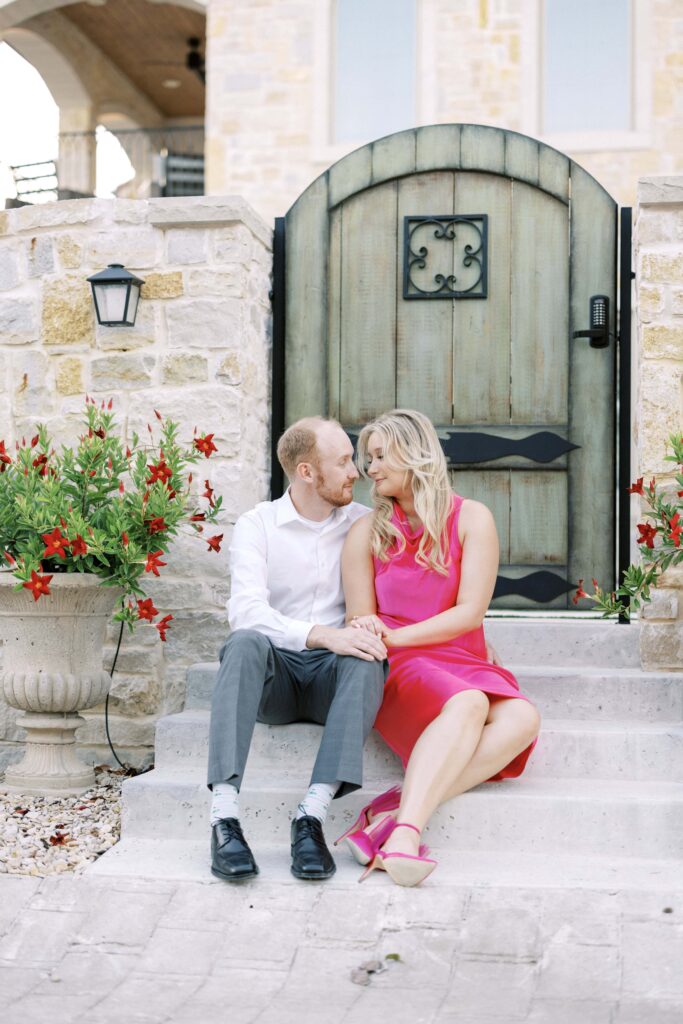 bride and groom sitting looking at each other during their Adriatica Village Engagement session