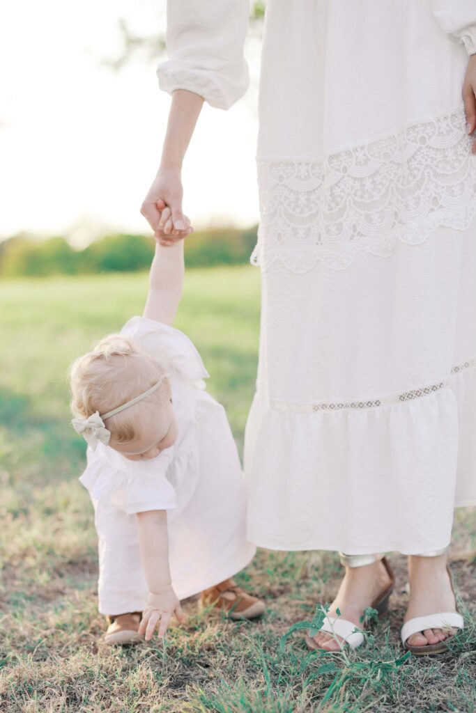 jessica holding her baby's hand as she is picking a flower during her Sansom Park family session