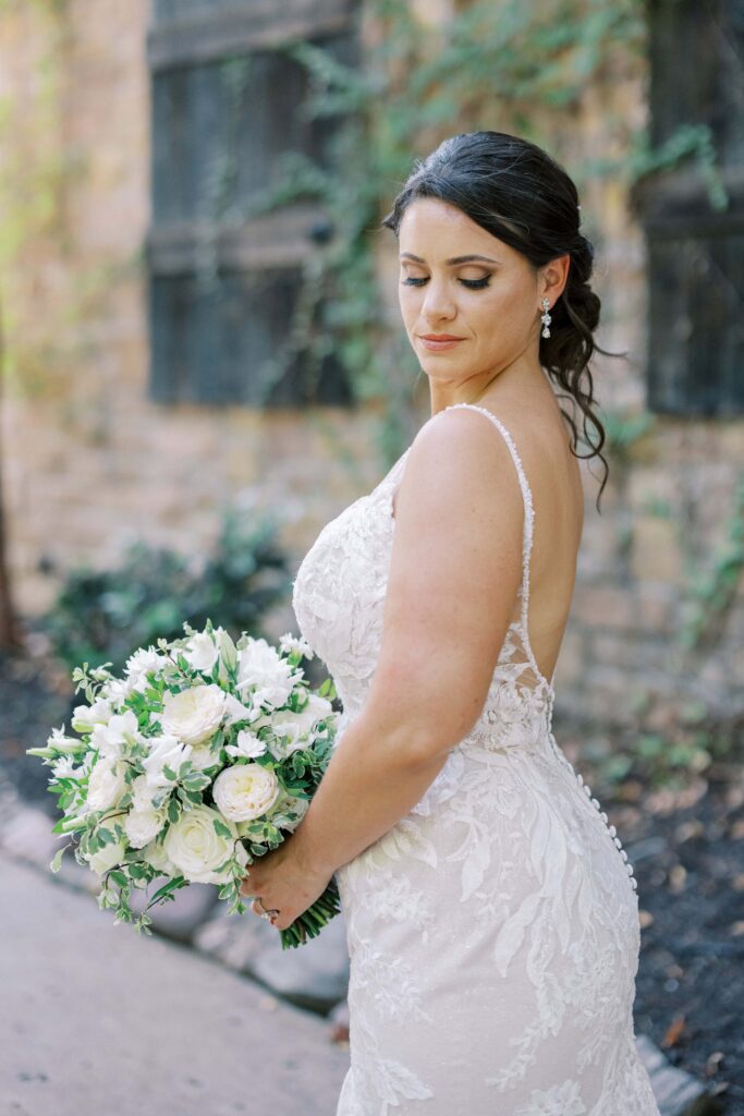 bridal portrait of whitney holding her bouquet and looking down at her shoulder at her aristide mansfield wedding