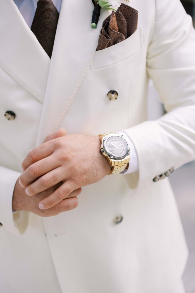 groom showing off his gold watch at his brighton abbey wedding