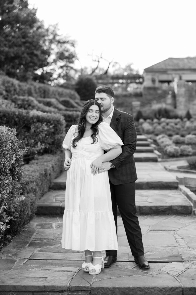 Caleb and Tori standing on the stairs of the rose Garden at their Fort Worth Botanic Garden Engagement 