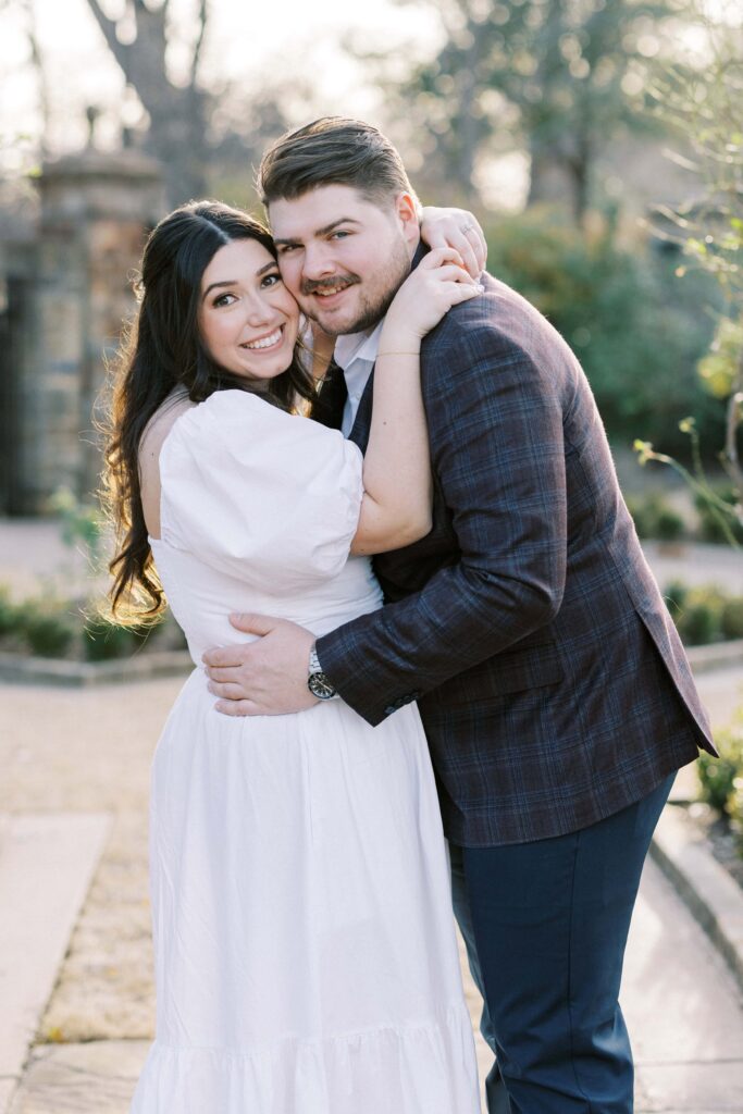 Caleb and Tori holding each other and looking at the camera at their Fort Worth Botanic Garden Engagement