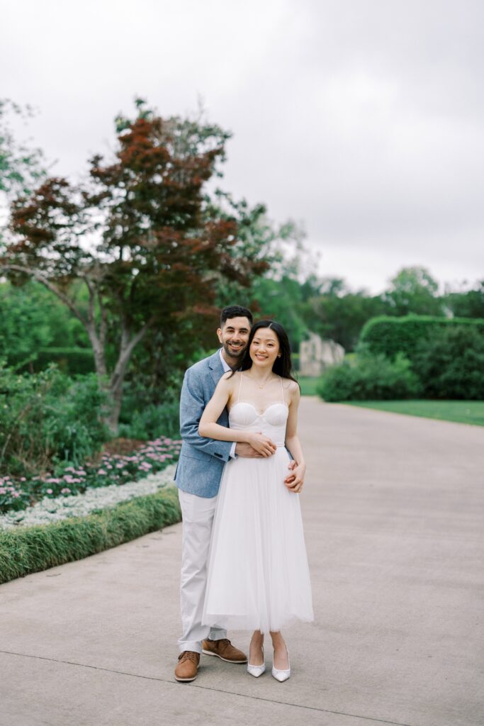 Rita and Alessandro hugging for their engagement photos at the Dallas Arboretum