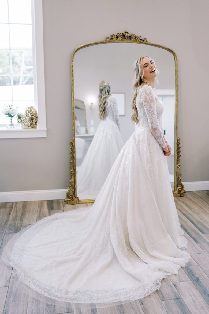 bride in fron of a floor length gold mirror in her wedding dress laughing at her Lakeview Hills Wedding
